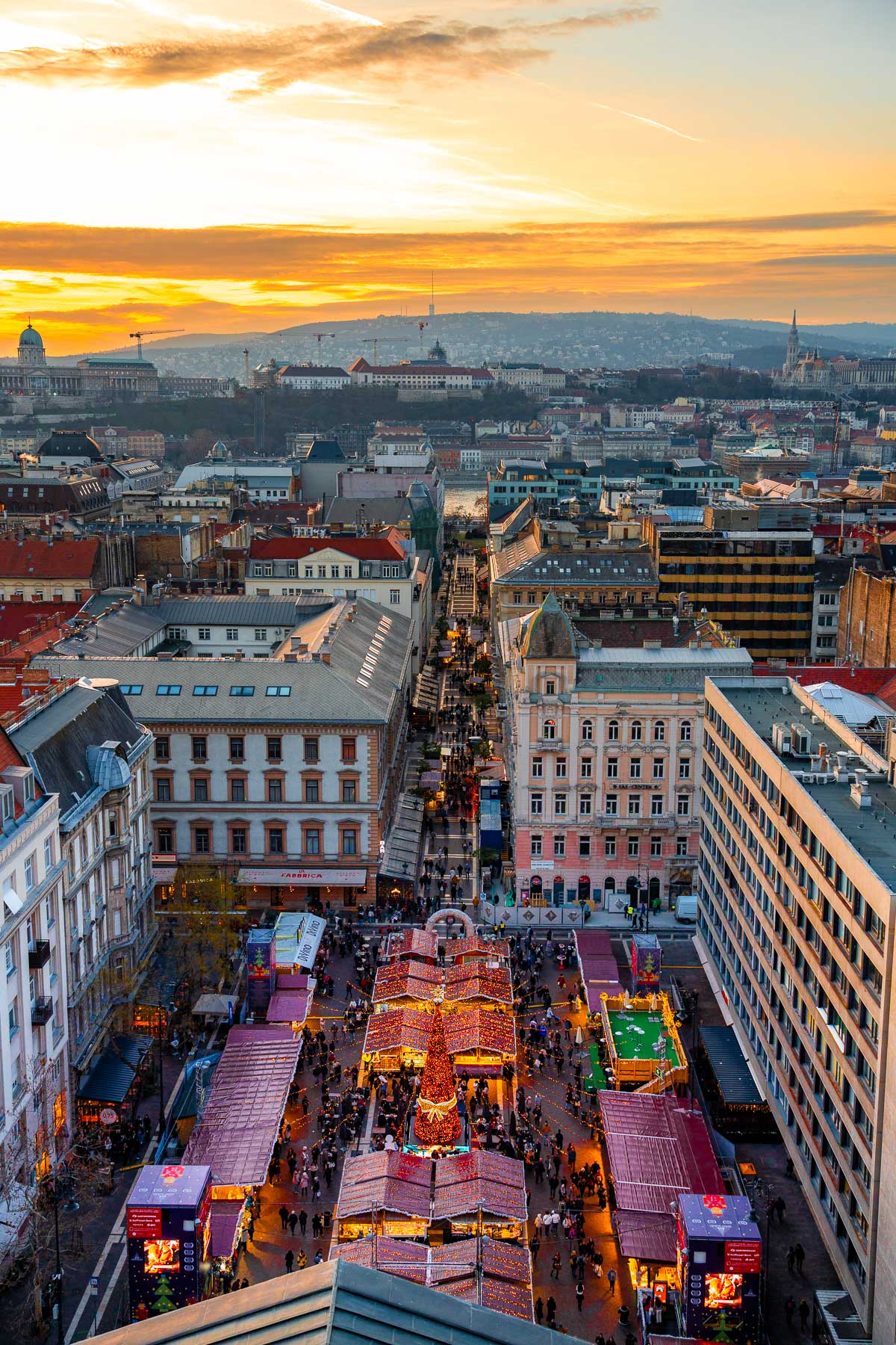 Aerial view of the Christmas market stalls lined up along the street near St. Stephen's Basilica in Budapest at sunset.