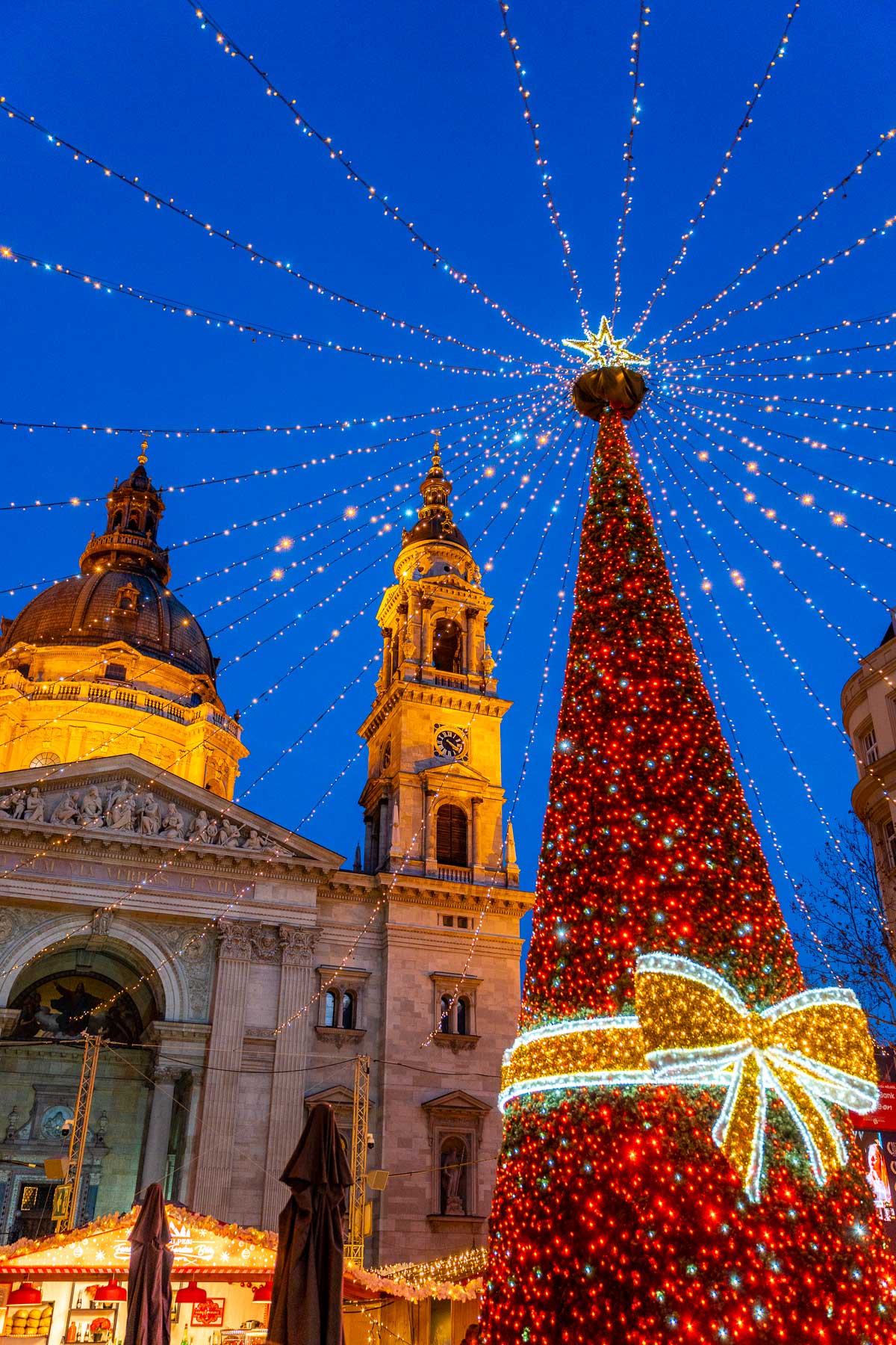 The Christmas tree and light canopy in front of St. Stephen's Basilica in Budapest during the evening.