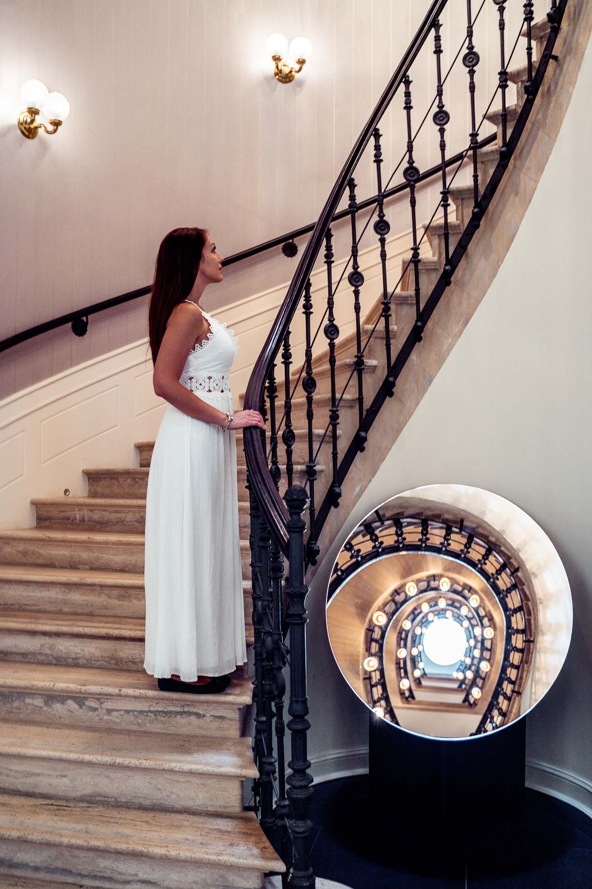 Girl in a white dress standing on a stairway at the Aria Hotel in Budapest
