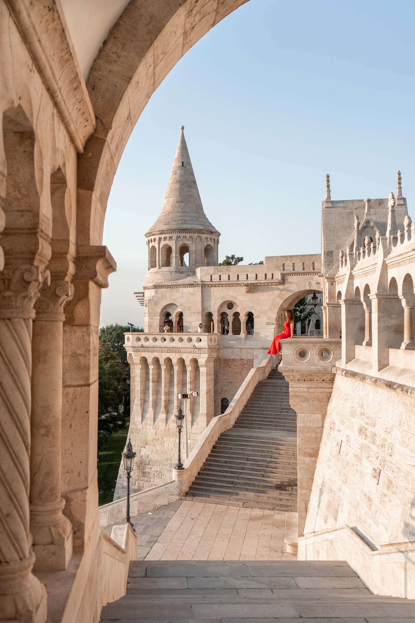 Girl in a red dress sitting at the Fisherman's Bastion in Budapest