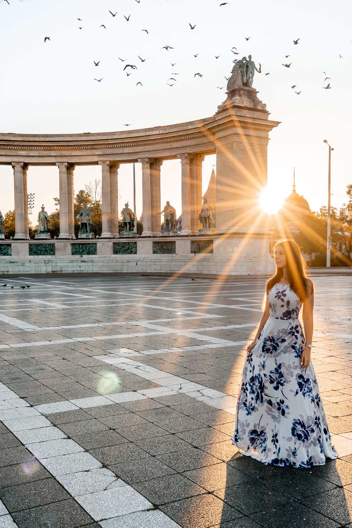 Girl in a blue floral dress standing in the middle of the Heroes Square in Budapest
