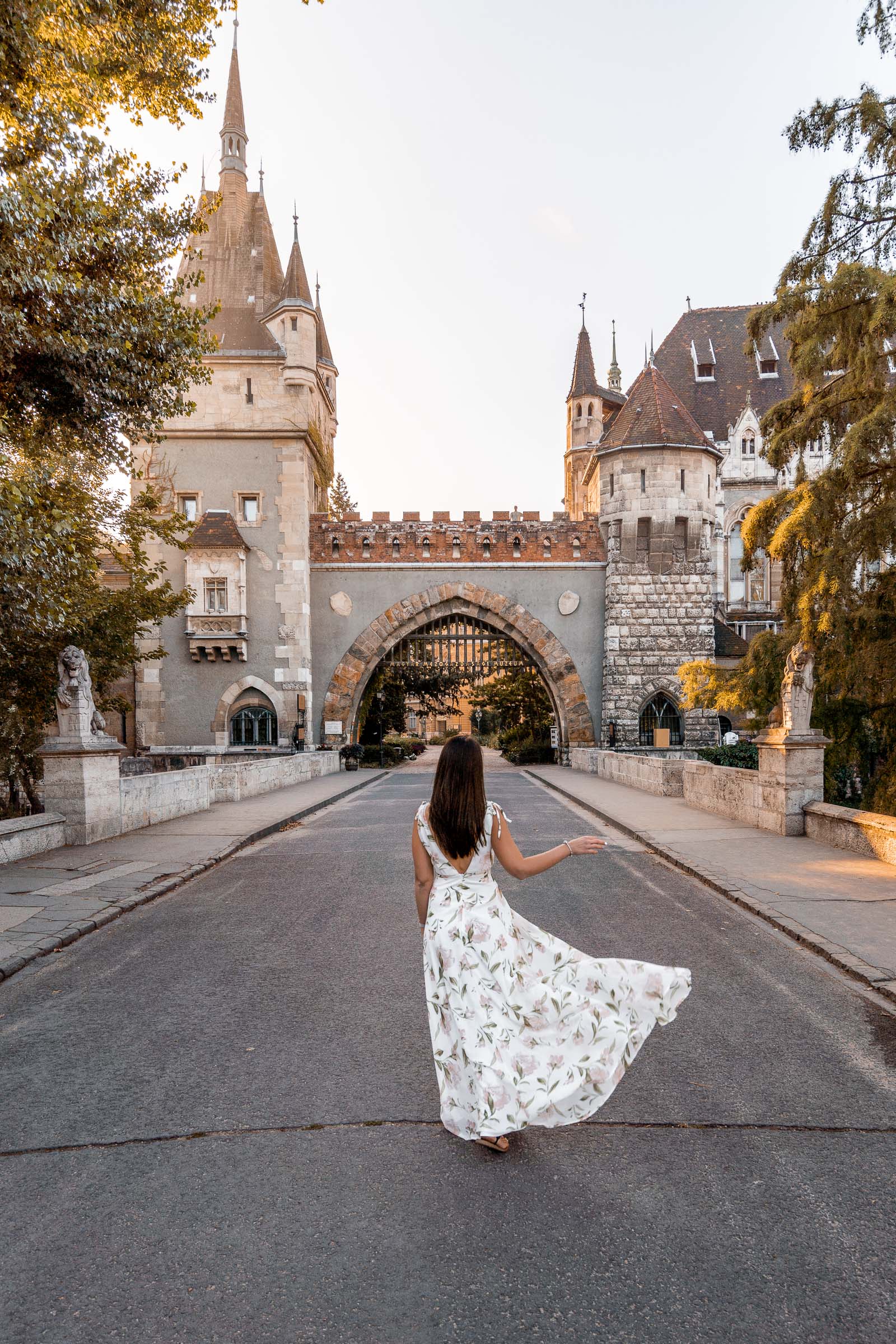 Girl in a white floral dress doing a skirt flip in front of the Vajdahunyad Castle in Budapest