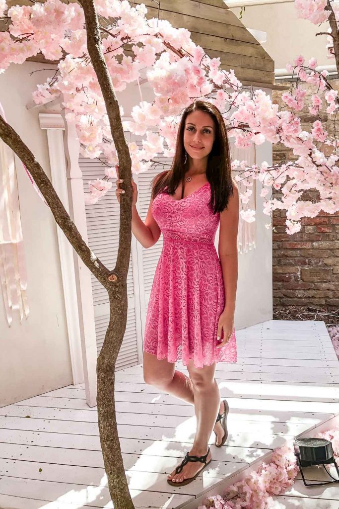 Girl in a pink dress standing under the cherry blossom trees at the Vintage Garden in Budapest