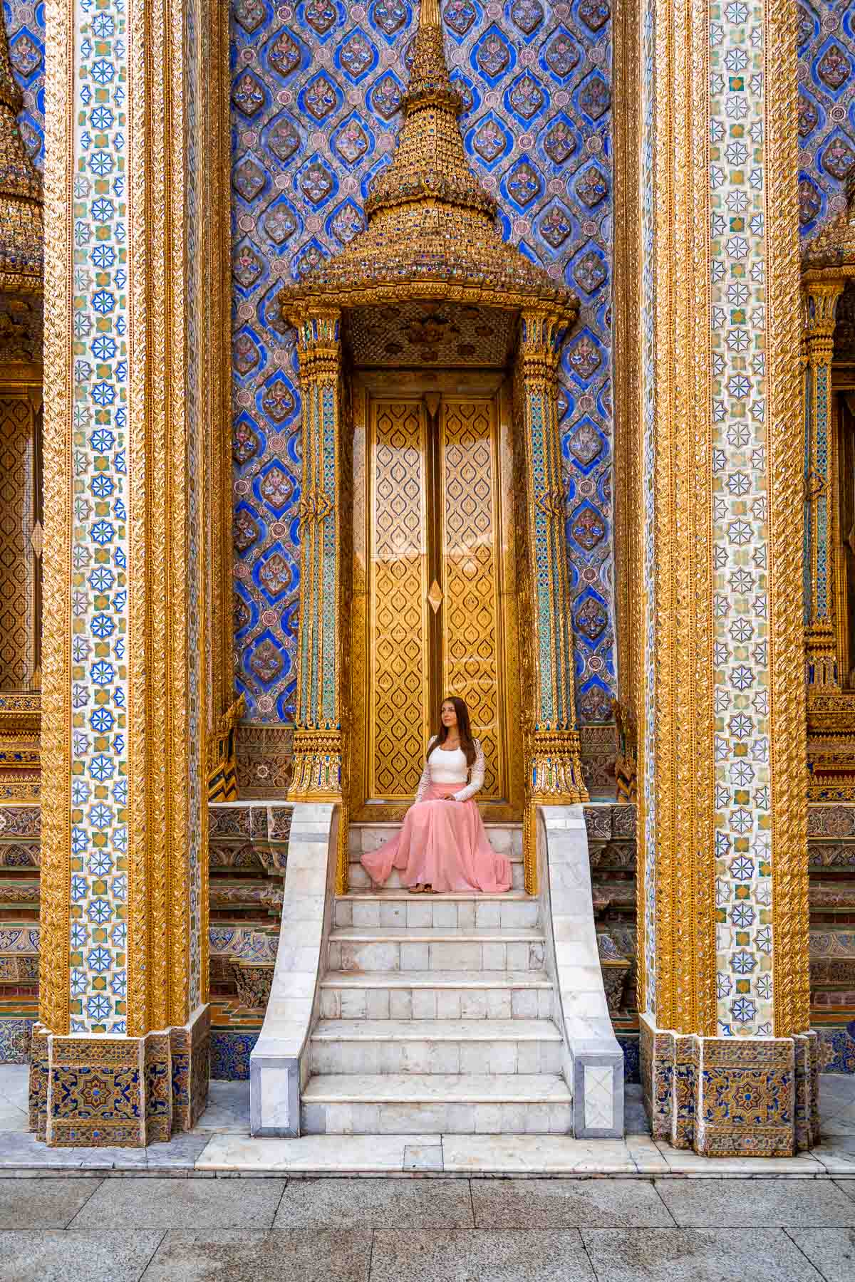 Girl in a pink skirt sitting on the stairs at the Grand Palace in Bangkok, Thailand