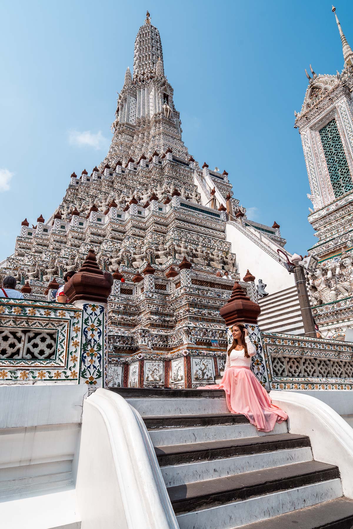 Girl in a pink skirt sitting on the stairs at Wat Arun in Bangkok