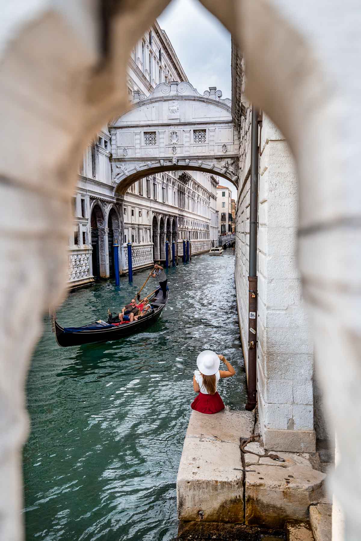 Girl in a red skirt sitting below the Bridge of Sighs in Venice, Italy