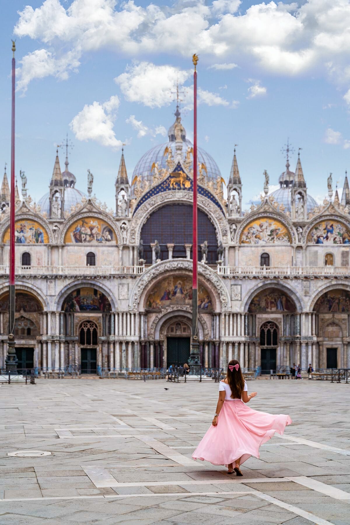 Girl in a pink skirt twirling in front of St. Mark's Basilica in Venice, Italy