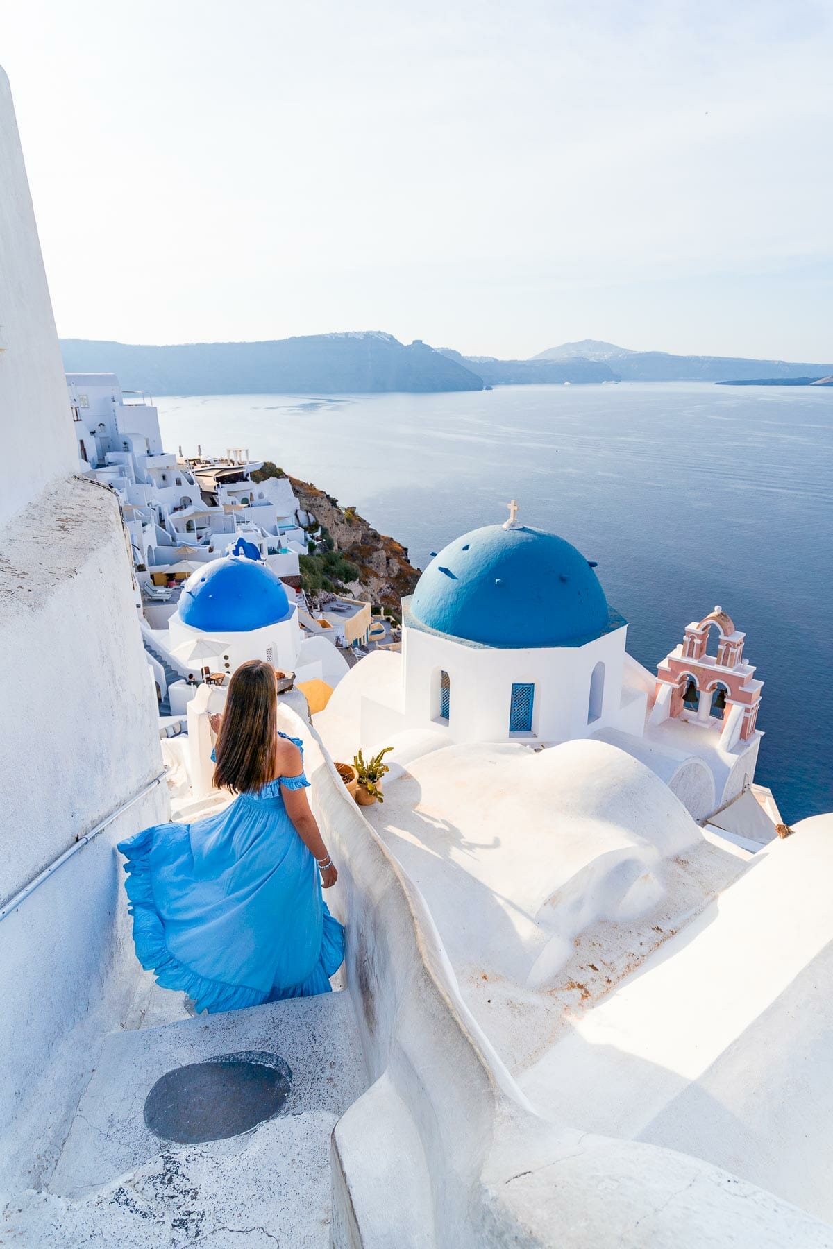 Girl in blue dress at the famous blue dome in Oia, Santorini