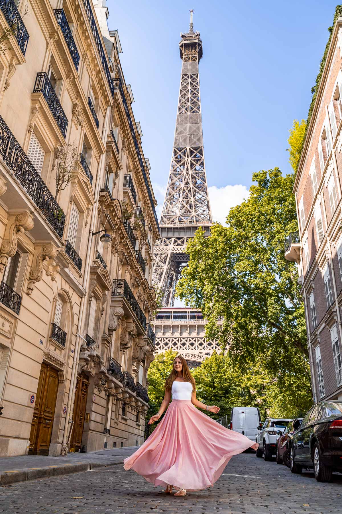 Girl in a pink skirt twirling in front of the Eiffel Tower in Rue de l'Université, one of the most instagrammable places in Paris