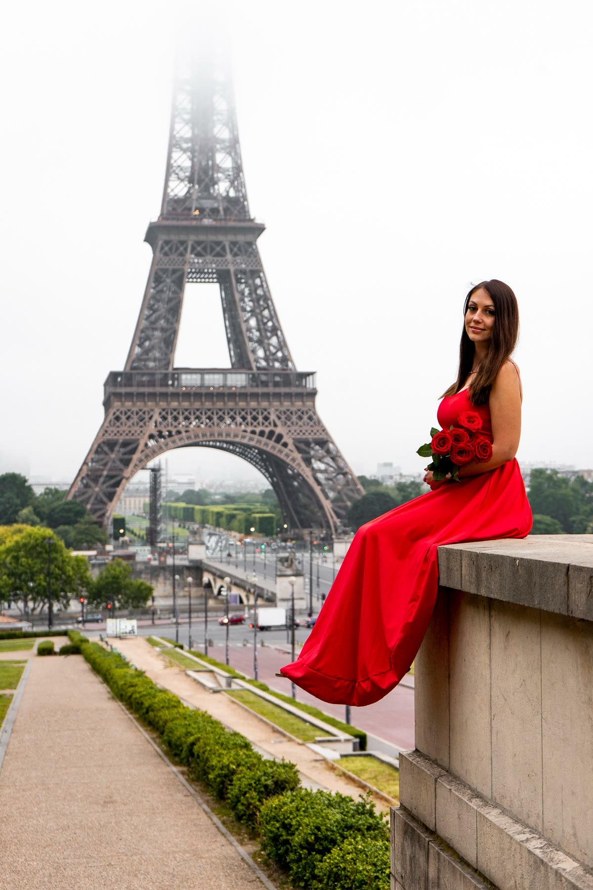 Girl in a red dress sitting at Trocadero in front of the Eiffel Tower
