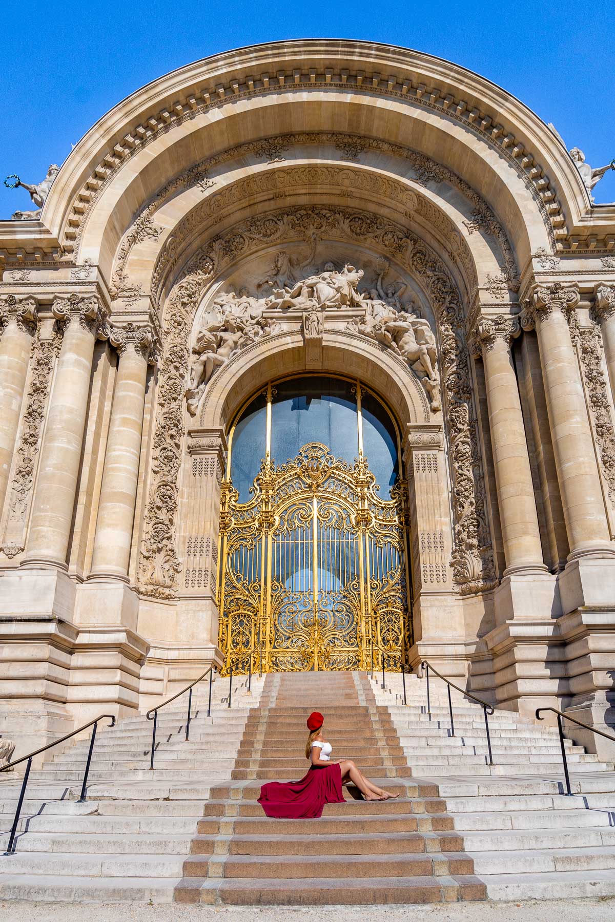 Girl in a red skirt sitting in front of Petit Palais in Paris