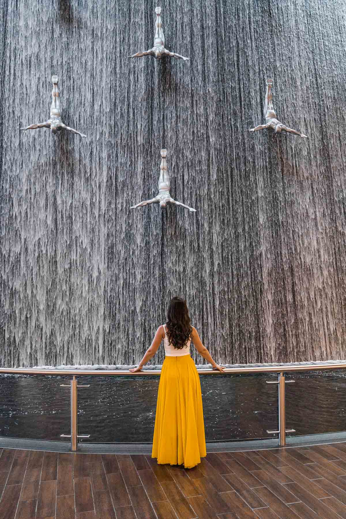 Girl in yellow skirt standing in front of the Waterfall Wall in the Dubai Mall
