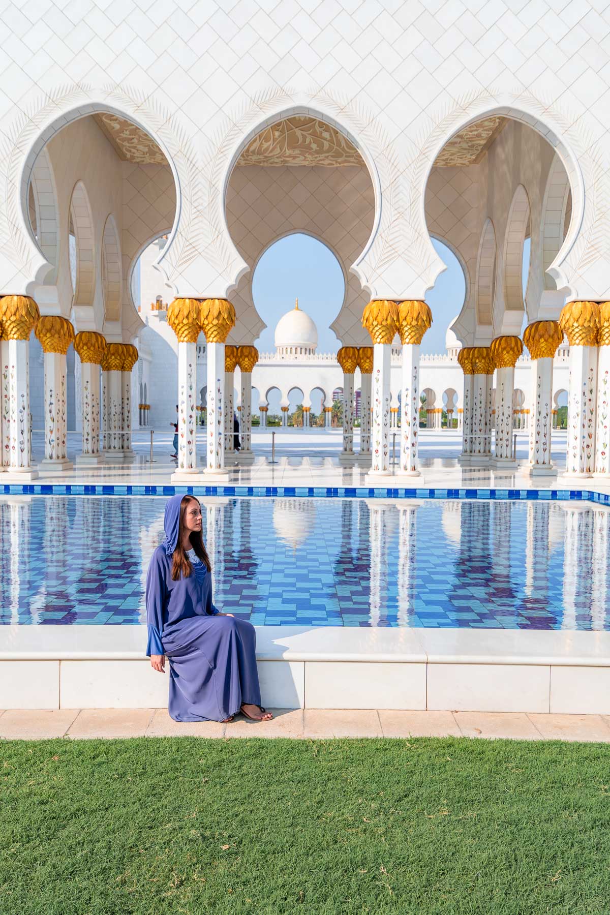Girl in a blue abaya sitting by the pool at Sheikh Zayed Grand Mosque, Abu Dhabi