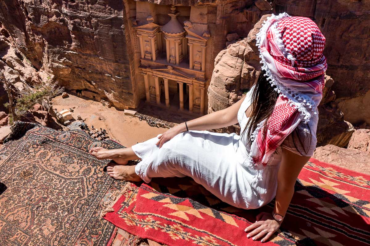 Girl in a white dress and a white-red keffiyeh sitting at the best Treasury viewpoint in Petra, Jordan