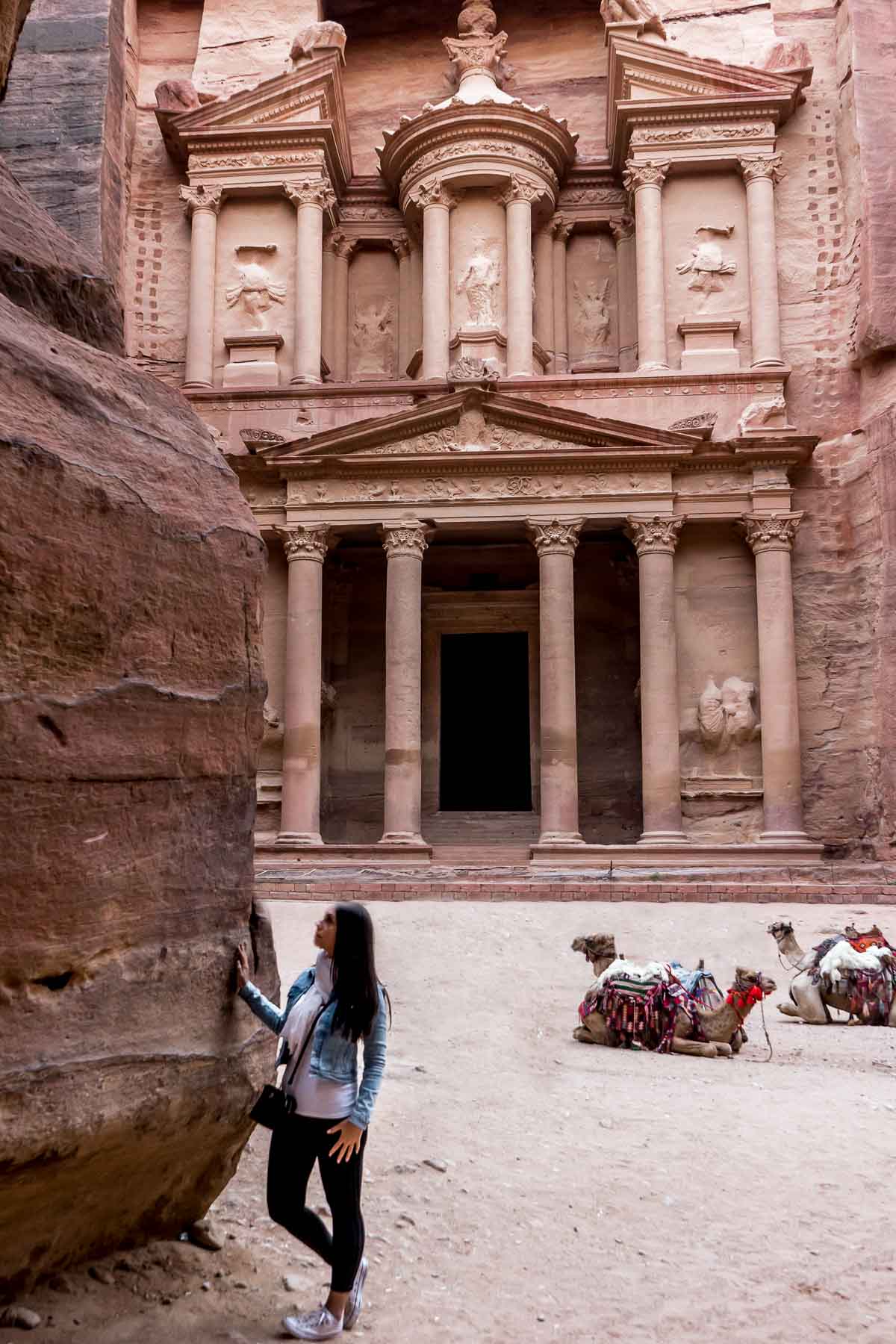 Girl in a denim jacket and jeans standing in front of the Treasury in Petra, Jordan