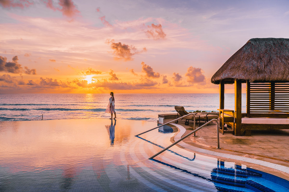 Girl walking on the edge of an infinity pool at sunrise at JW Marriott Cancun