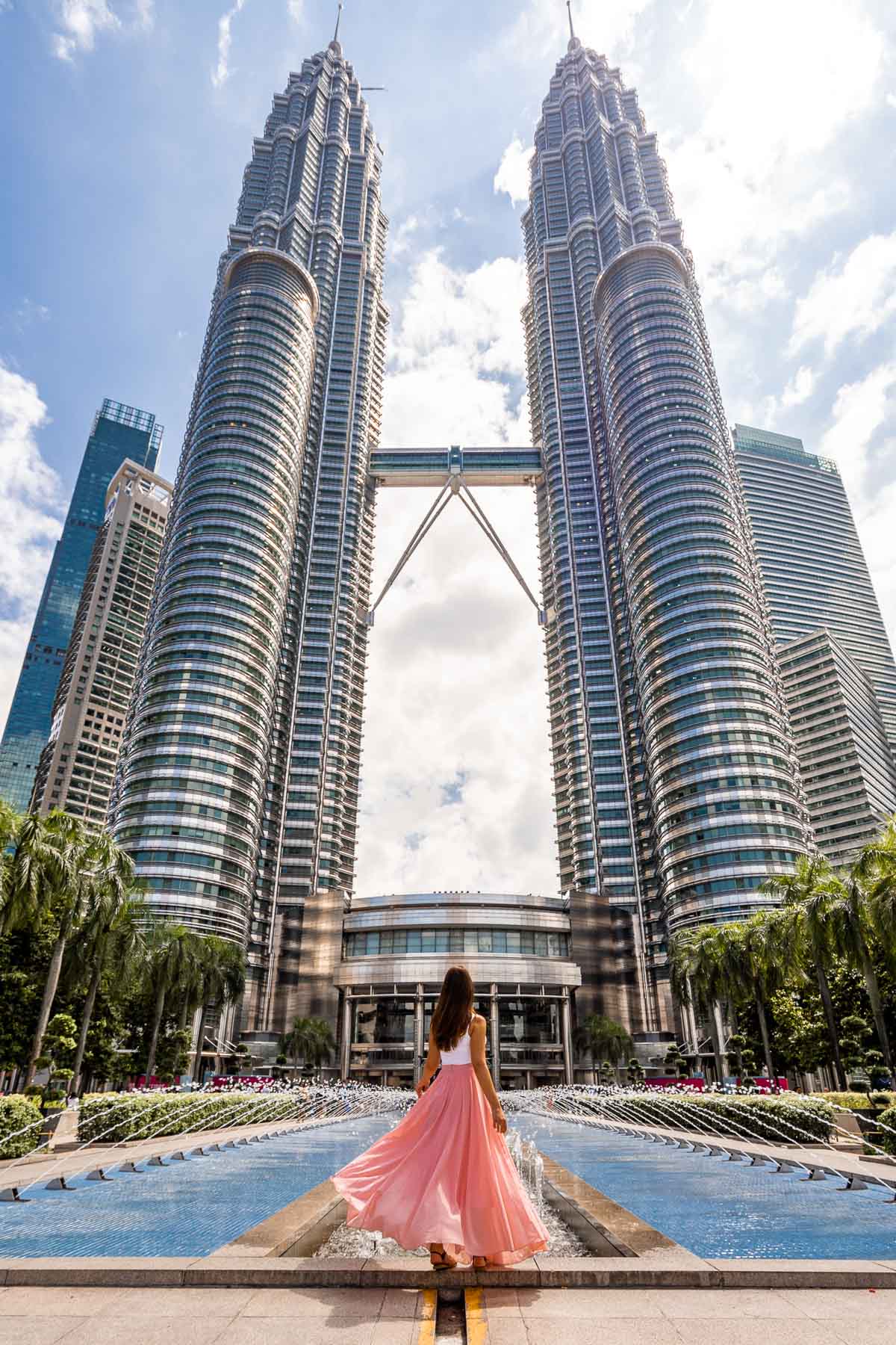 Girl in pink skirt in front of the Petronas Towers, Kuala Lumpur