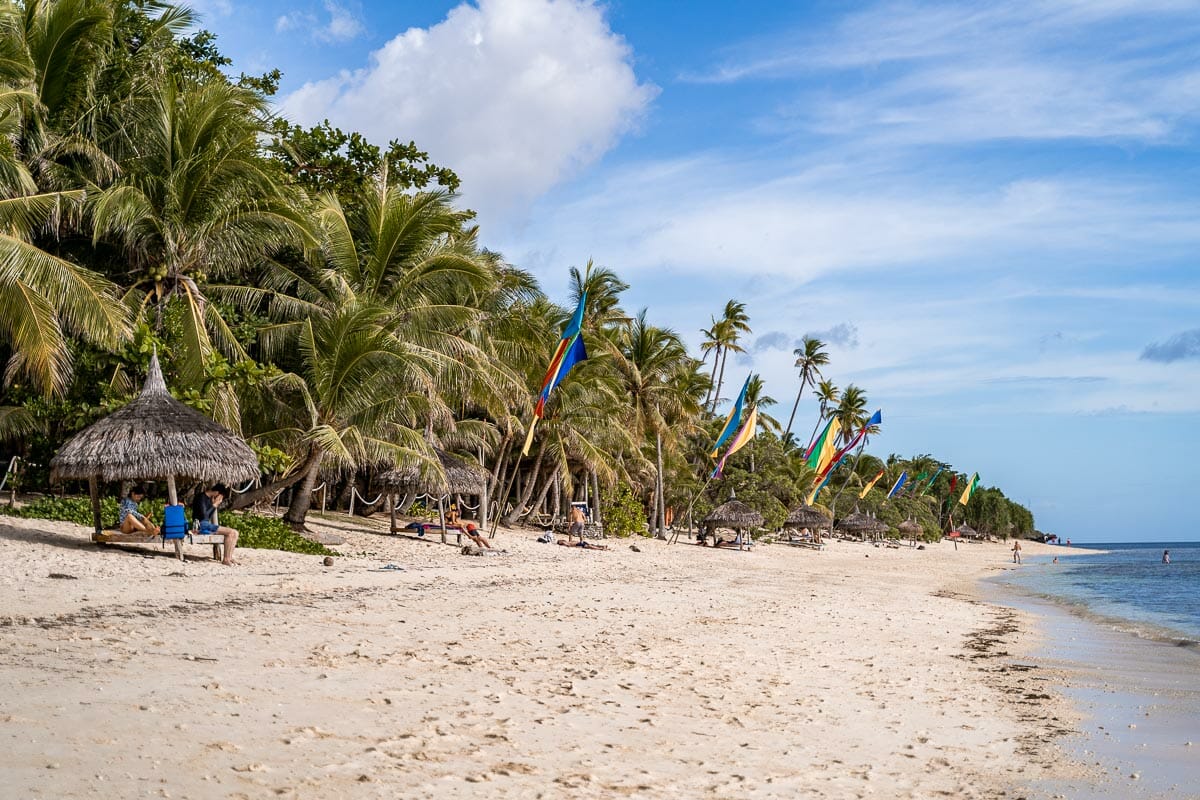 White sandy beach lined with palm trees at Tubod Beach & Marina Sanctuary, Siquijor