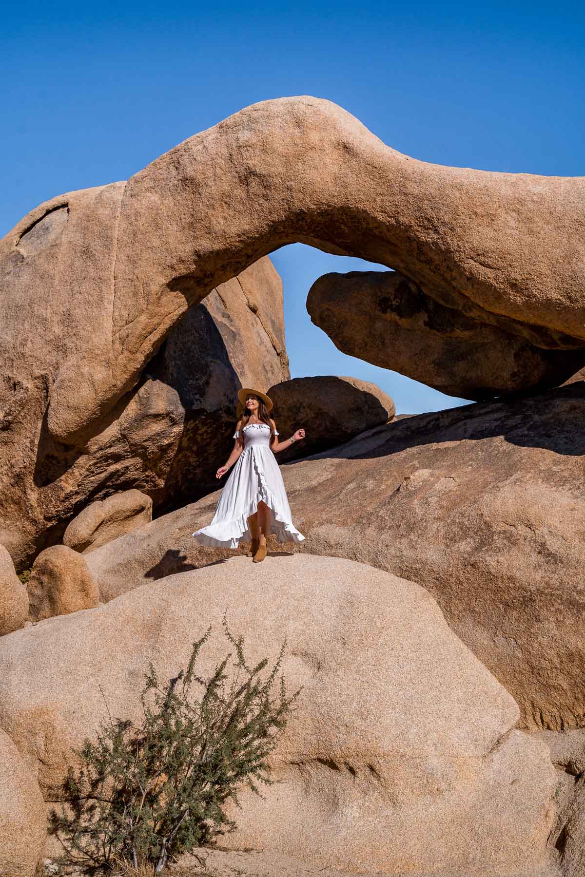 Girl in white dress at the Arch Rock in Joshua Tree National Park