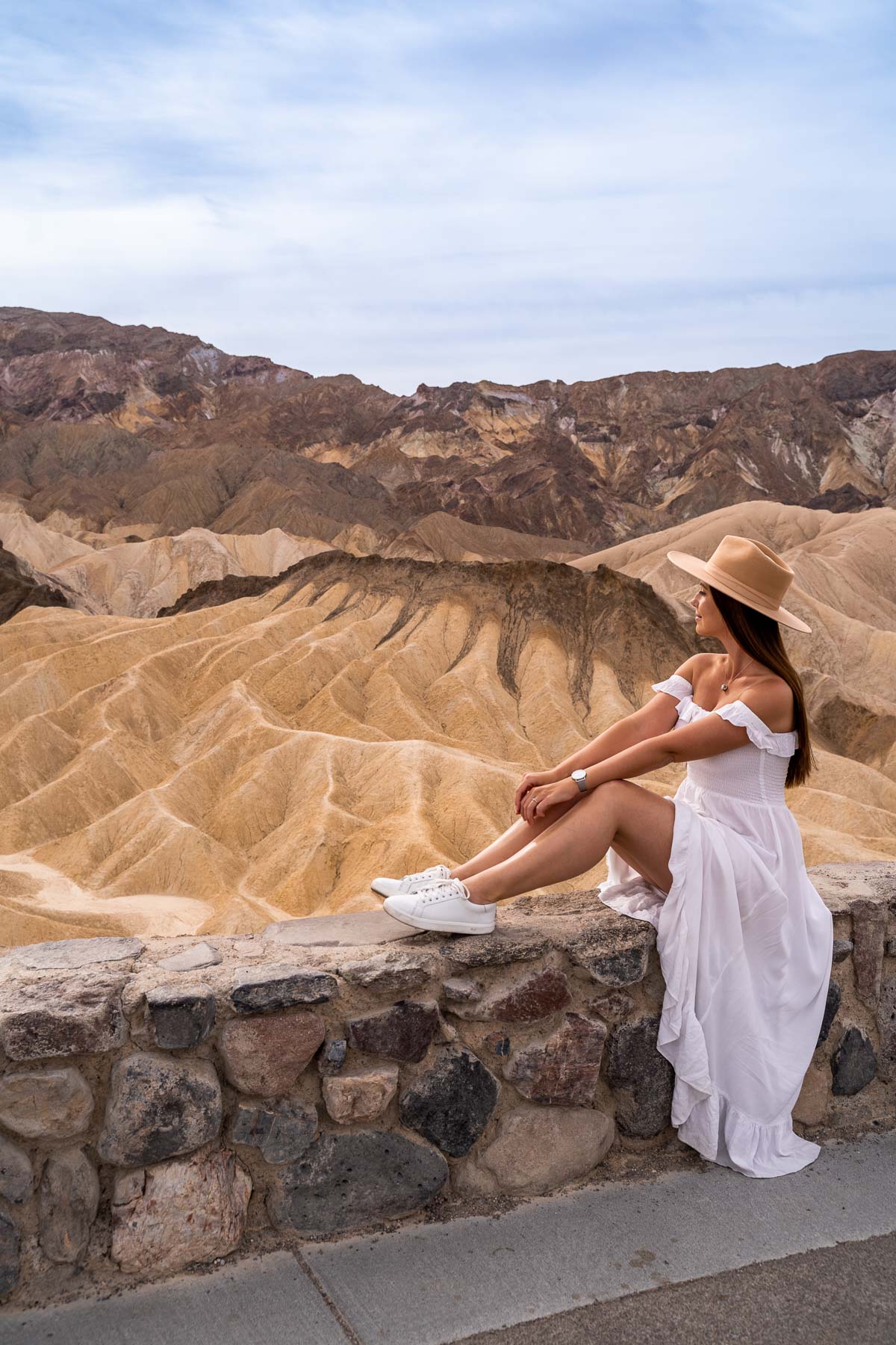 Girl in white dress sitting at Zabriskie Point in Death Valley National Park