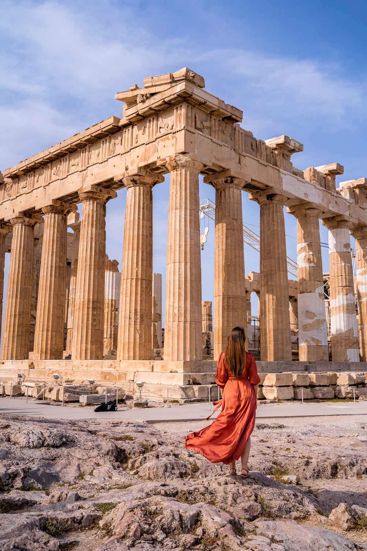 Girl in orange dress in front of the Partheon in Acropolis, Athens