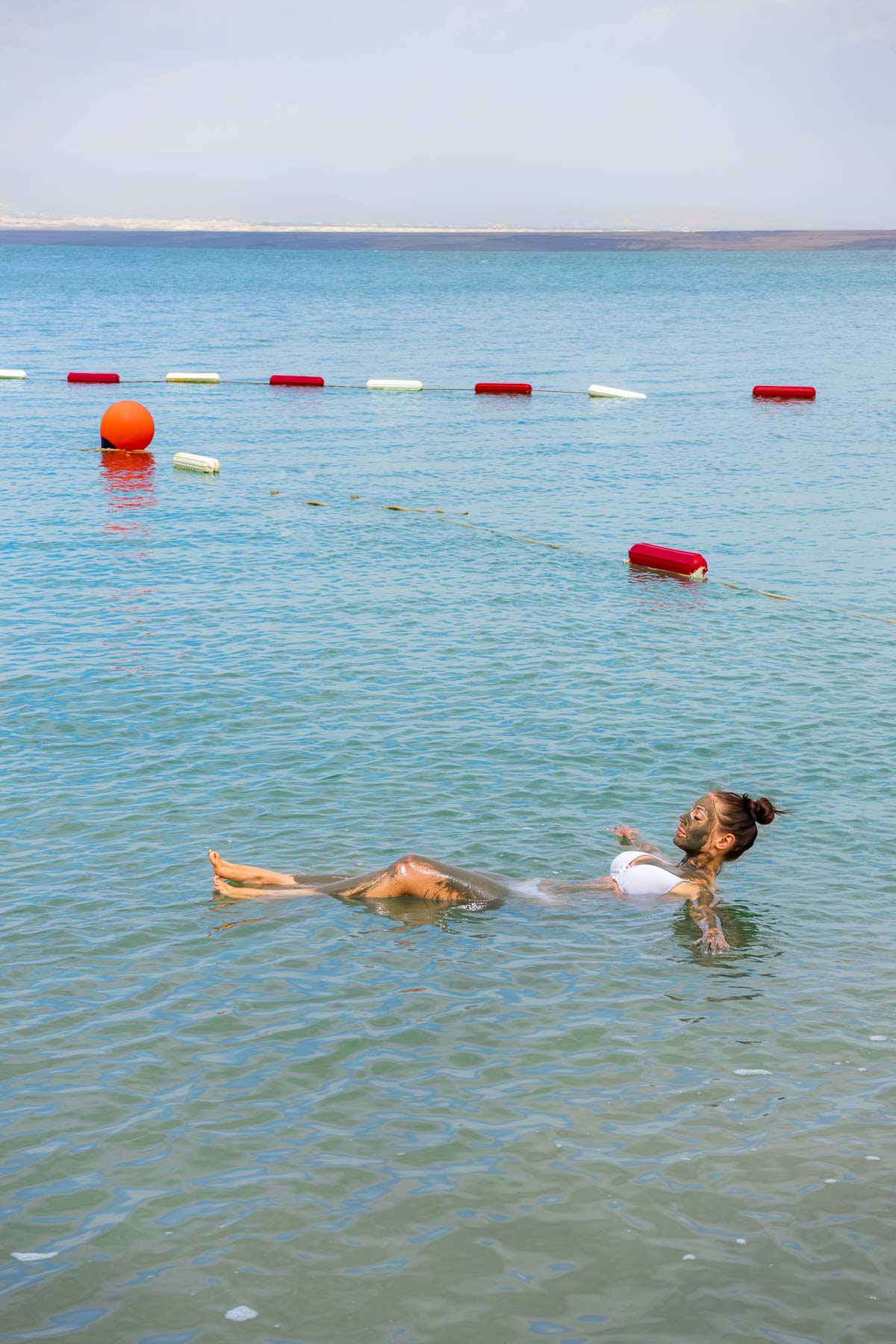 Girl in a straw hat floating in the Dead Sea in Jordan