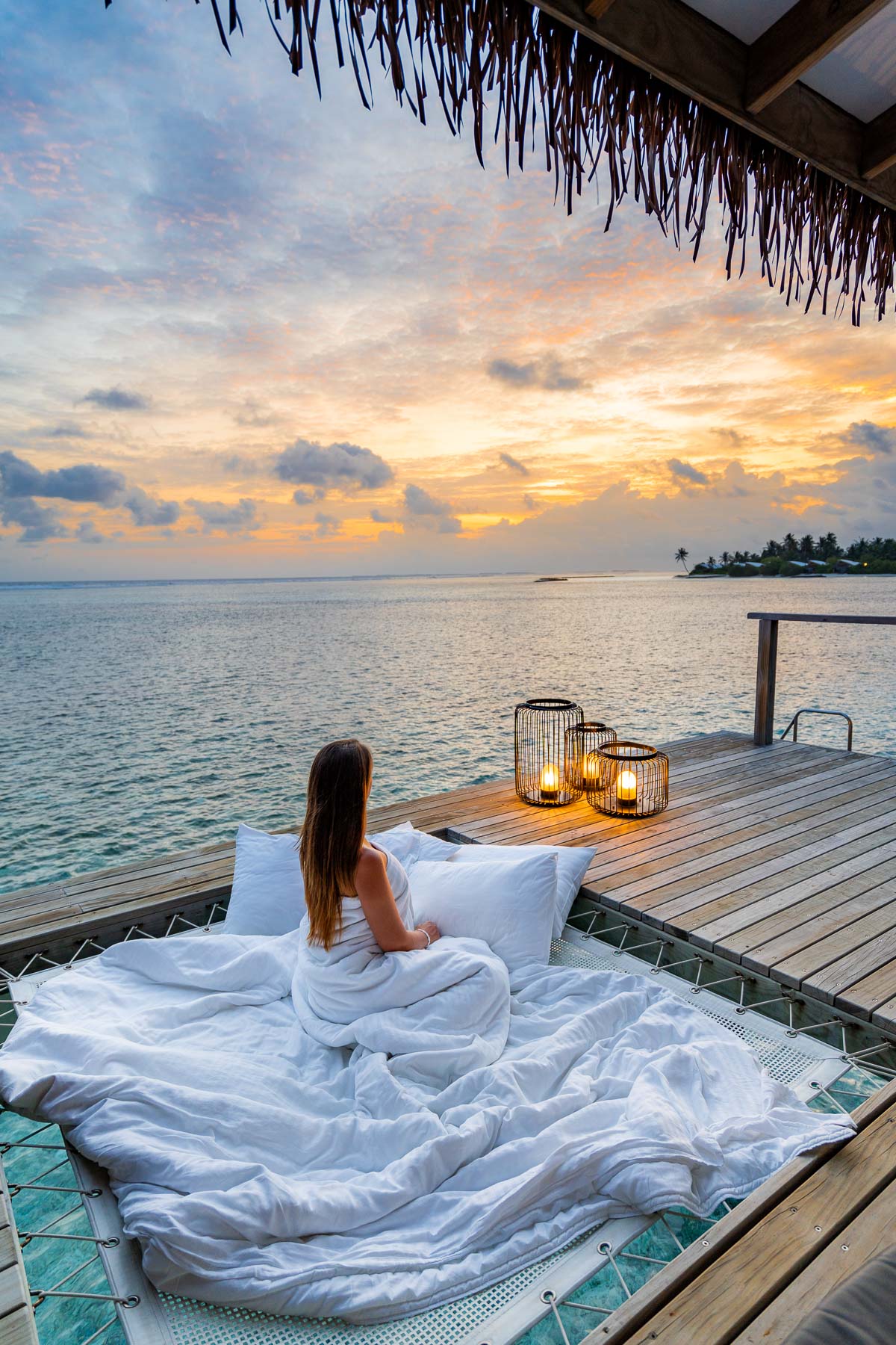 Girl watching the sunset from a water bungalow at Cinnamon Hakuraa Huraa Maldives