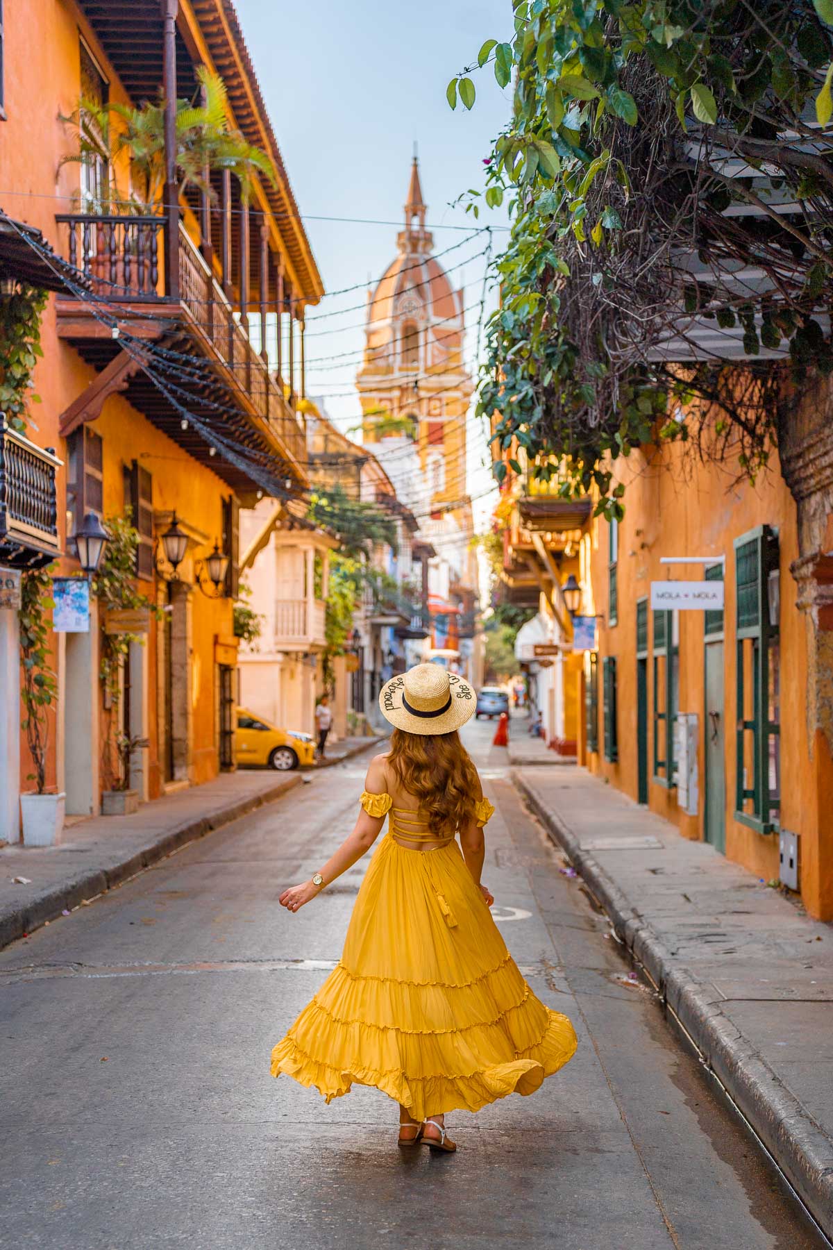 Girl on a colorful street in Cartagena overlooking Catedral de Santa Catalina de Alejandria
