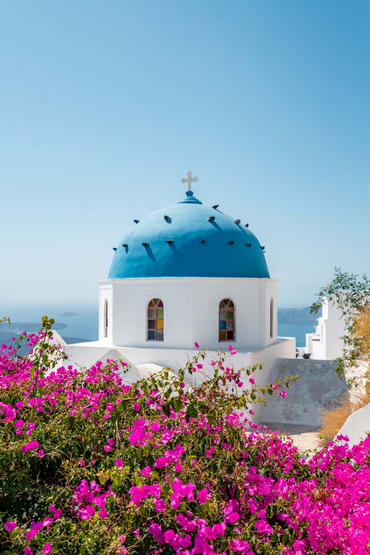 Blue domed church with pink bougainvillea in Imerovigli, Santorini
