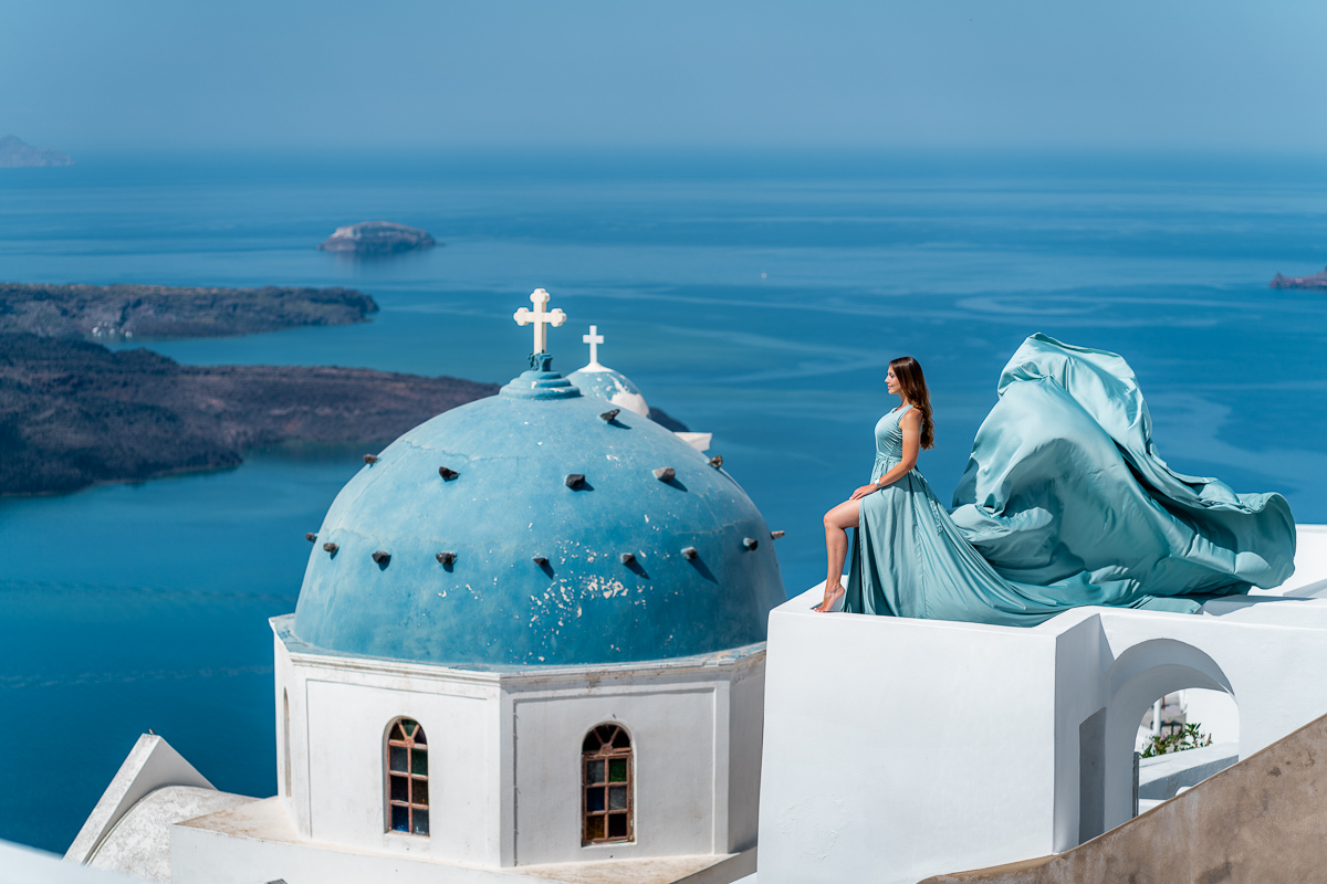 Girl in a blue flying dress on a rooftop in Imerovigli, Santorini