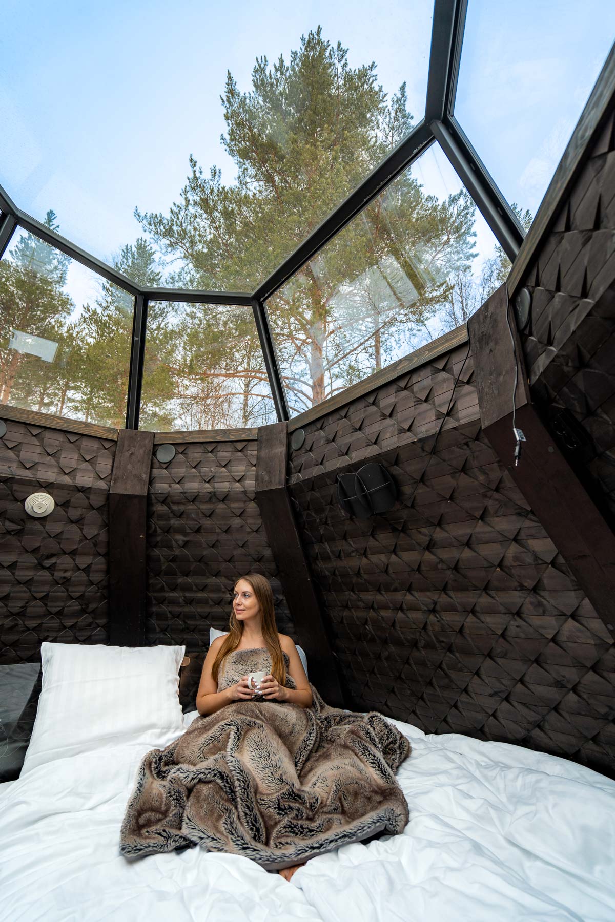 Girl in bed at the Kammi Glass Igloo Suite at Apukka Resort
