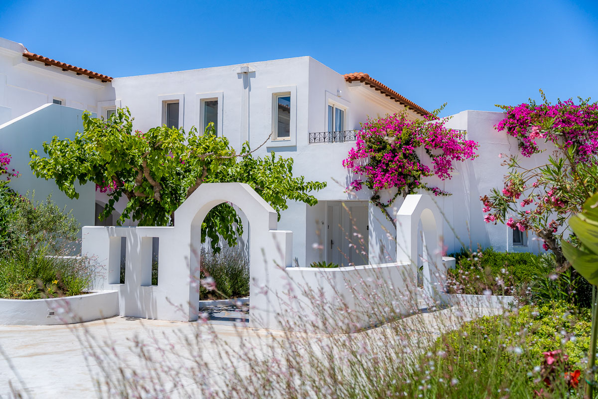 White building with pink bougainvillea flowers at Grecotel Caramel