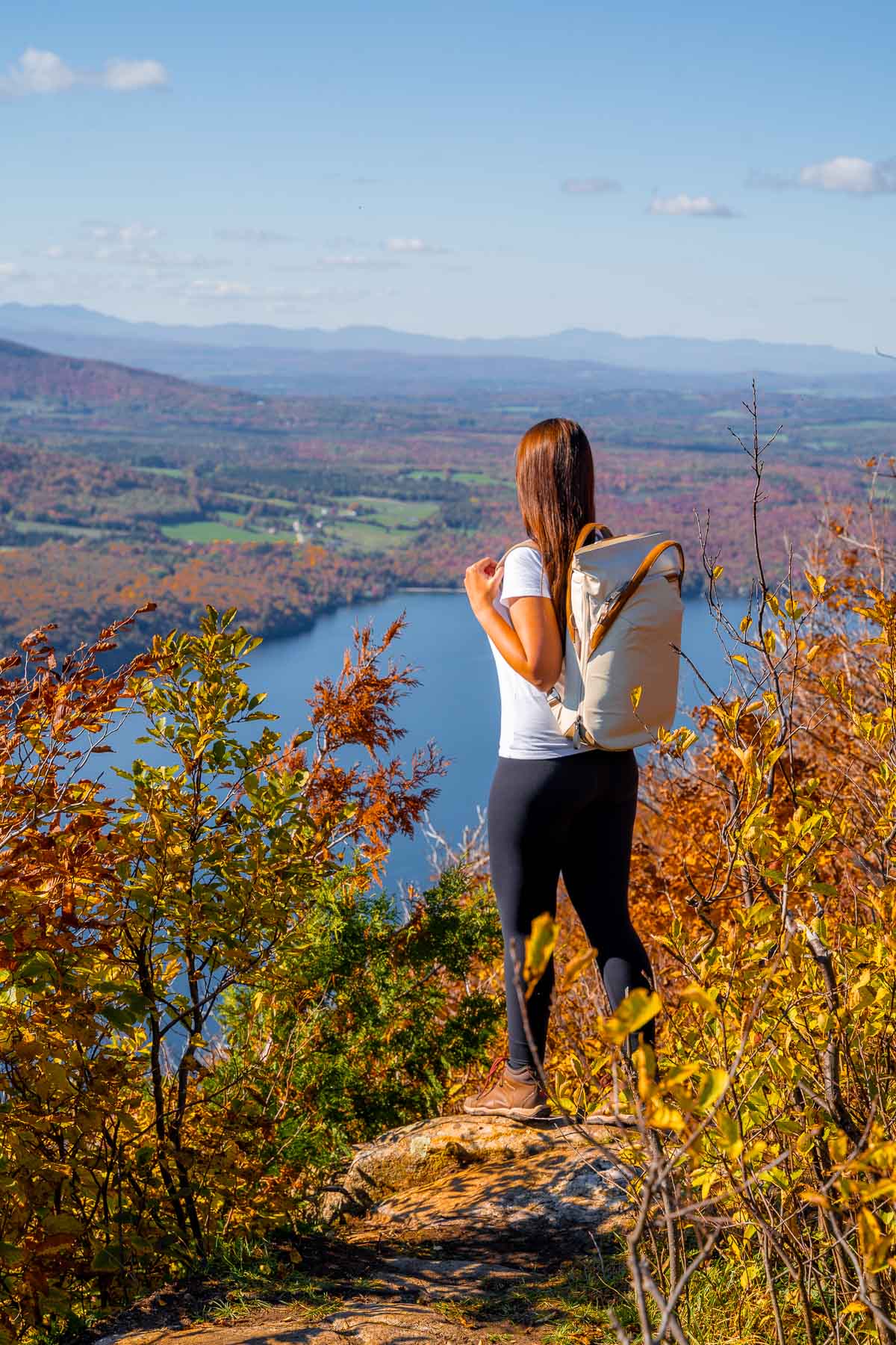 Girl standing on top of Mount Pisgah overlooking Lake Willoughby in Vermont in the fall