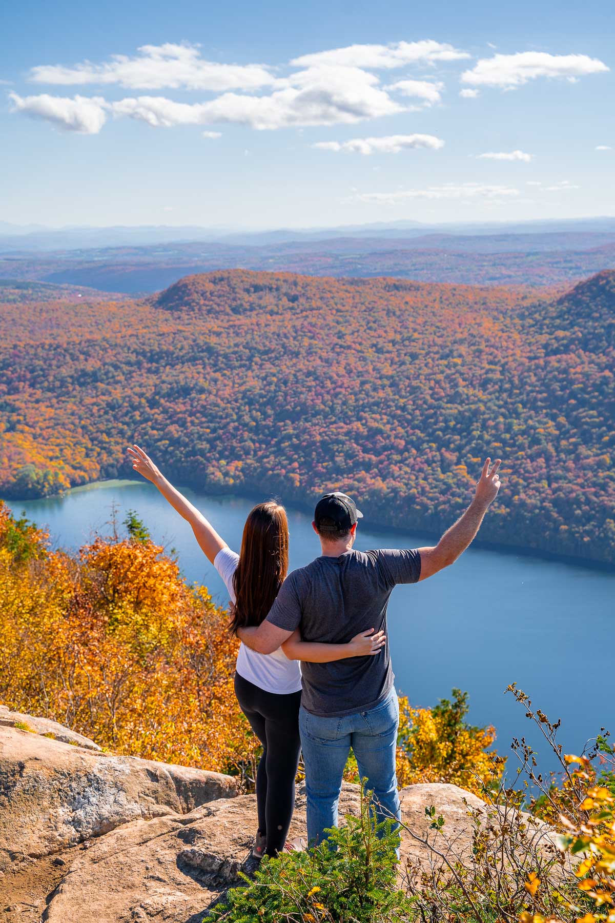 Couple standing on top of Mount Pisgah overlooking Lake Willoughby in Vermont in the fall