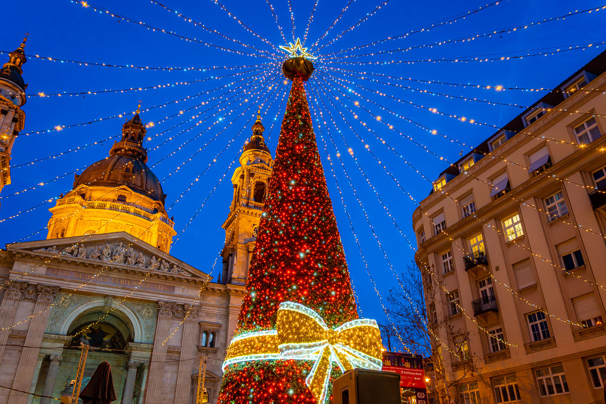 The Christmas tree and light canopy in front of St. Stephen's Basilica in Budapest during the evening.