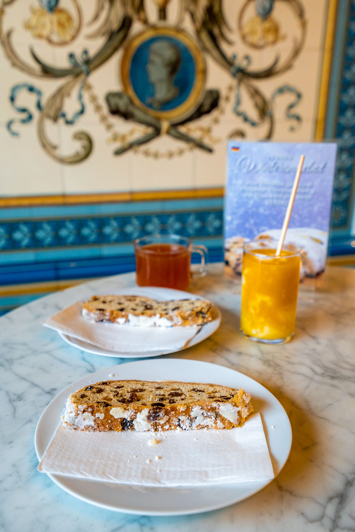 Two slices of traditional Dresden stollen served with tea and juice on a marble table inside Dresdner Molkerei Gebrüder Pfund.