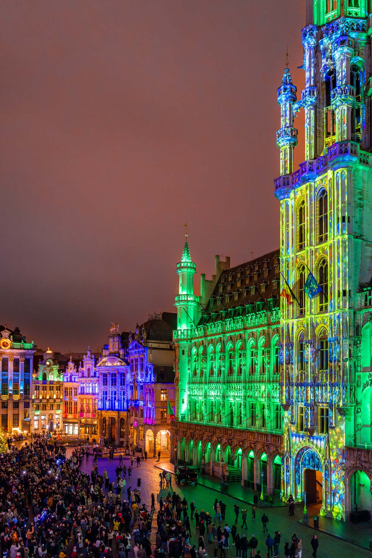 Crowds gathered at the Grand Place in Brussels watching colorful light projections illuminating the historic buildings during the city’s Christmas celebrations.