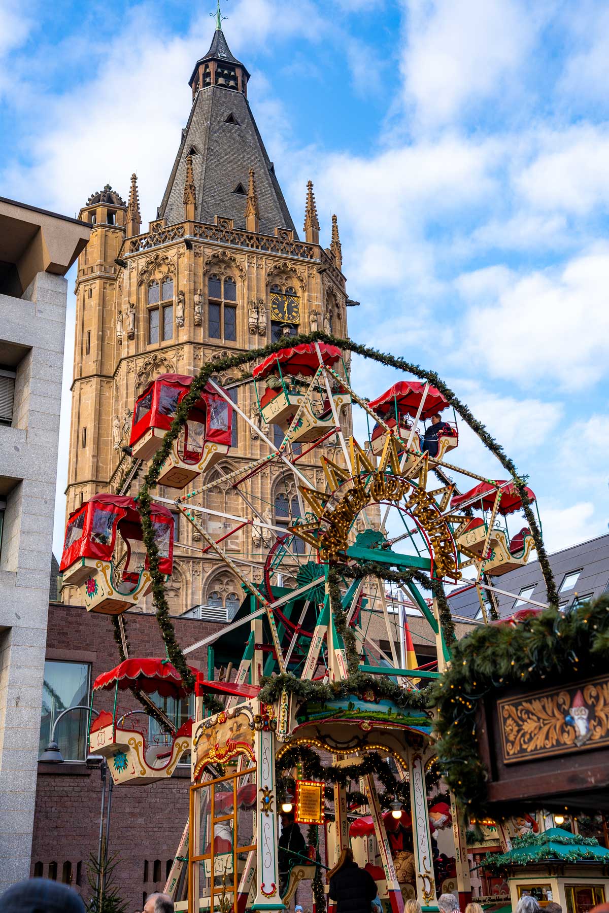 Small Ferris wheel set up in front of a historic tower at Heinzels Wintermärchen in Cologne.